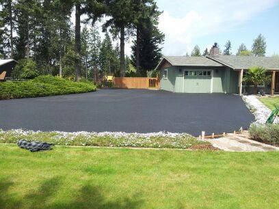 Paved driveway leading to a light green house