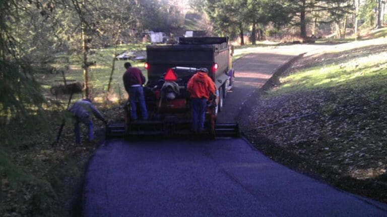 3 men on the back of an asphalt dumper