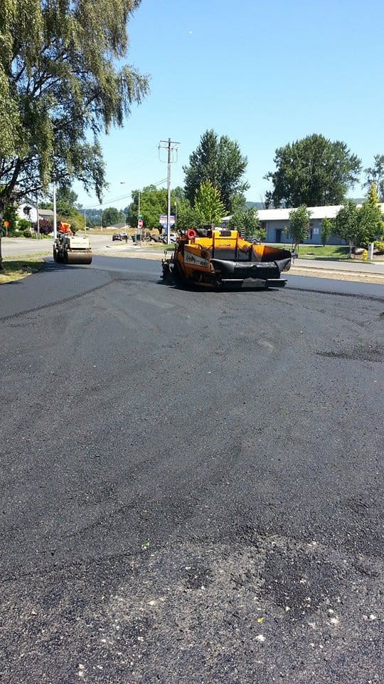 Tar dumper and road roller paving a road.