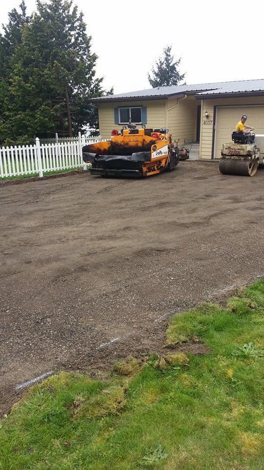 Road roller and asphalt paver on a dirt road