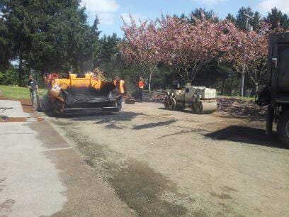 Asphalt paver getting ready to dump asphalt on a dirt road