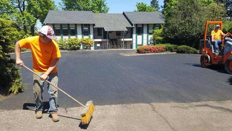 Worker brushing debris of newly paved road