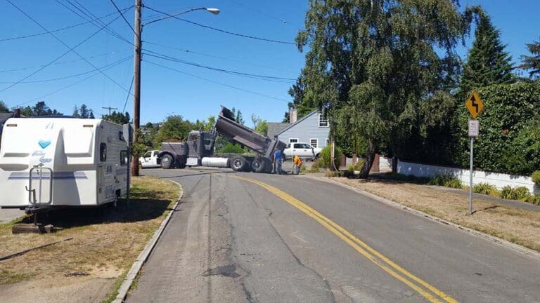 Dump truck dumping rocks and refuse off side of road